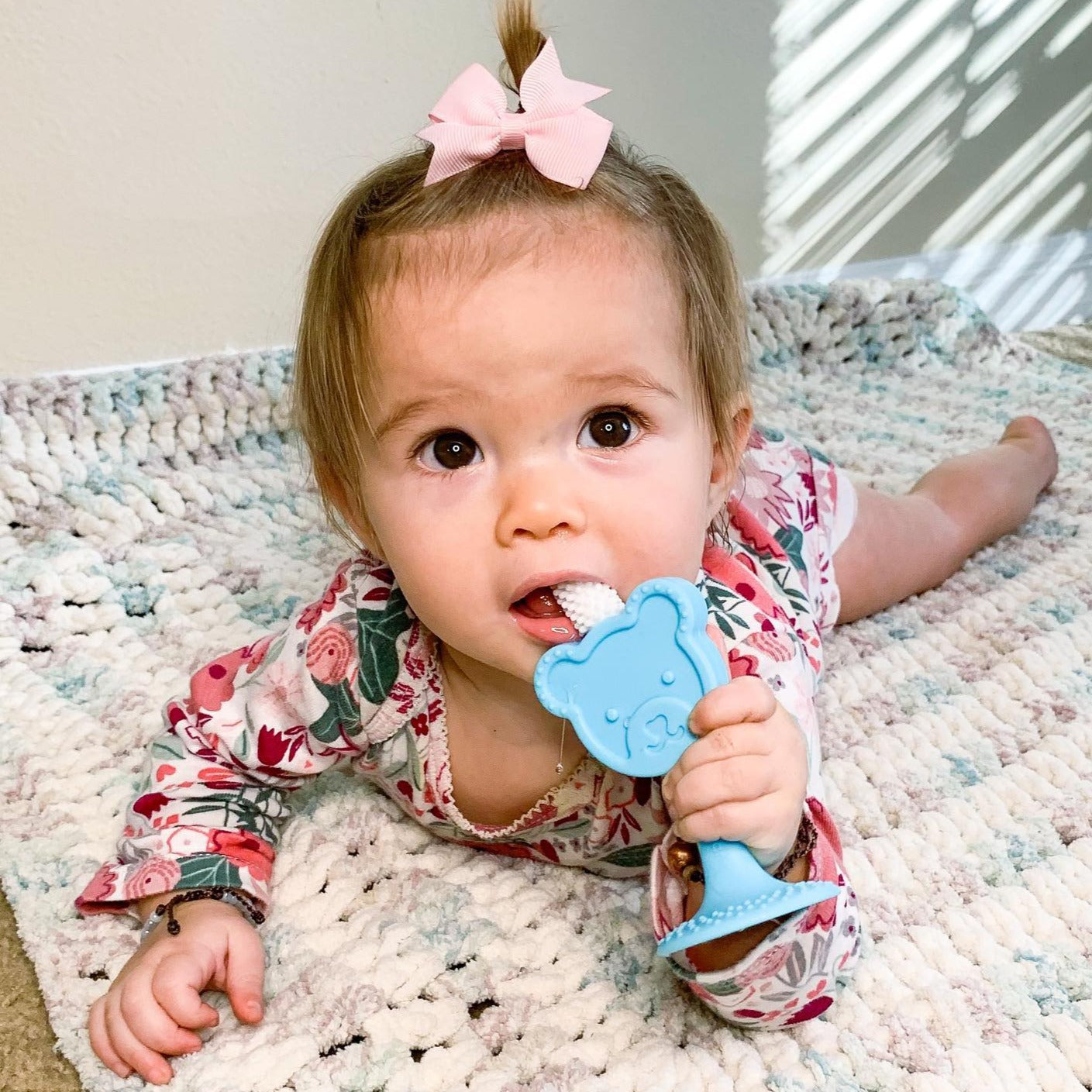 Baby holding oogiebear 360° teething toothbrush